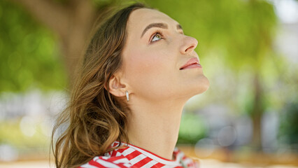 Young blonde woman looking to the sky with relaxed expression at park