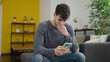 © Krakenimages.com - Young hispanic man using smartphone worried sitting on the sofa at home