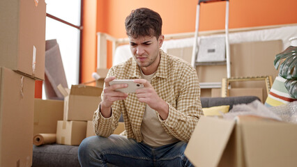 Sticker - Young hispanic man using smartphone looking upset at new home