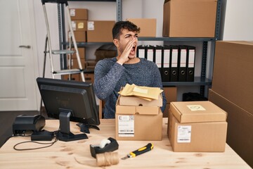 Canvas Print - Young hispanic man working at small business ecommerce using smartphone looking confident with smile on face, pointing oneself with fingers proud and happy.