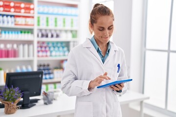 Poster - Young beautiful hispanic woman pharmacist using touchpad working at pharmacy