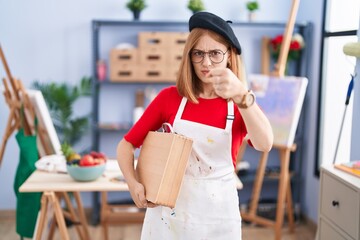 Sticker - Young redhead woman at art studio holding art case angry and mad raising fist frustrated and furious while shouting with anger. rage and aggressive concept.