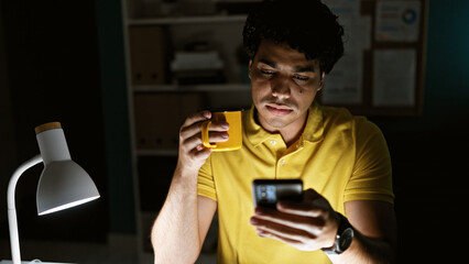 Poster - Young latin man business worker using smartphone drinking coffee at the office