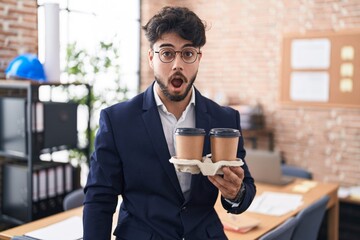 Sticker - Hispanic man with beard working at the office holding coffee scared and amazed with open mouth for surprise, disbelief face