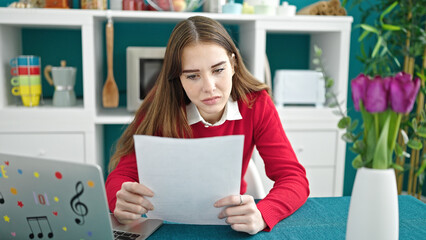 Poster - Young hispanic woman using laptop reading document at dinning room