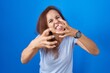 © Krakenimages.com - Brunette woman standing over blue background shouting frustrated with rage, hands trying to strangle, yelling mad