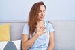 © Krakenimages.com - Young woman touching heart sitting on sofa at home