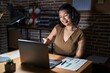 © Krakenimages.com - Young hispanic woman working at the office at night smiling friendly offering handshake as greeting and welcoming. successful business.