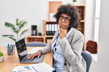 Sticker - Black woman with curly hair wearing call center agent headset at the office with hand on chin thinking about question, pensive expression. smiling with thoughtful face. doubt concept.