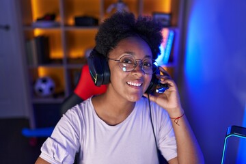 Poster - African american woman streamer smiling confident sitting on table at gaming room