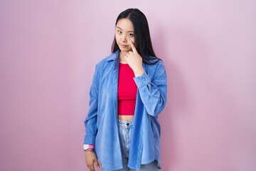 Poster - Young asian woman standing over pink background pointing to the eye watching you gesture, suspicious expression