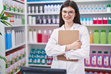 Wall Mural - Young caucasian woman pharmacist smiling confident holding clipboard at pharmacy