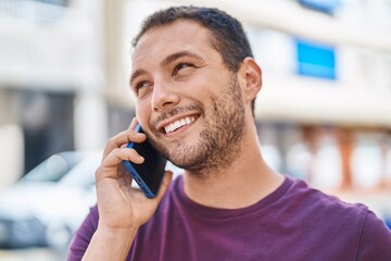 Young man smiling confident talking on the smartphone at street