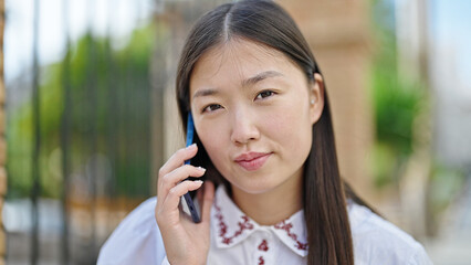 Sticker - Young chinese woman talking on smartphone with serious expression at street