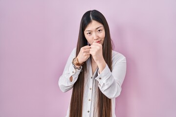 Wall Mural - Chinese young woman standing over pink background ready to fight with fist defense gesture, angry and upset face, afraid of problem