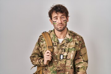 Canvas Print - Hispanic young man wearing camouflage army uniform looking sleepy and tired, exhausted for fatigue and hangover, lazy eyes in the morning.