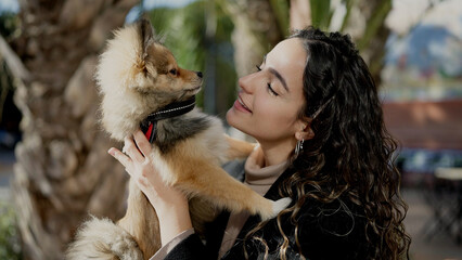 Wall Mural - Young hispanic woman with dog smiling confident standing at park