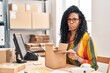 Middle age hispanic woman working at small business ecommerce looking inside box making fish face with mouth and squinting eyes, crazy and comical.