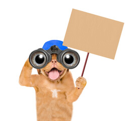 Aufkleber - Happy mastiff puppy wearing blue cap looks through binoculars and shows empty placard. Isolated on white background
