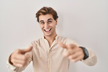 Wall Mural - Young man standing over isolated background pointing fingers to camera with happy and funny face. good energy and vibes.