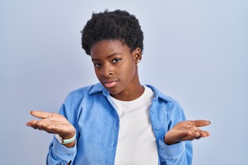 Canvas Print - African american woman standing over blue background clueless and confused with open arms, no idea concept.