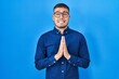 © Krakenimages.com - Young hispanic man wearing glasses over blue background begging and praying with hands together with hope expression on face very emotional and worried. begging.