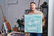 © Krakenimages.com - Young hispanic painter man holding canvas angry and mad screaming frustrated and furious, shouting with anger. rage and aggressive concept.