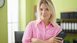 © Krakenimages.com - Young blonde woman business worker smiling confident holding smartphone at office