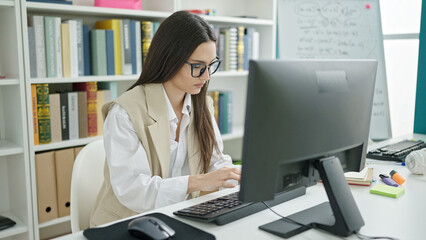 Young beautiful hispanic woman student using computer studying at university classroom