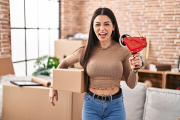 Wall Mural - Young woman moving to a new home packing boxes angry and mad screaming frustrated and furious, shouting with anger. rage and aggressive concept.