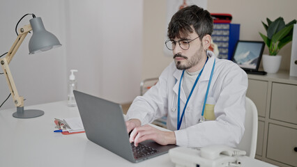 Poster - Young hispanic man doctor using laptop working at clinic