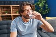 © Krakenimages.com - Middle age man drinking glass of water sitting on sofa at home