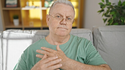 Poster - Middle age grey-haired man sitting on sofa suffering for wrist pain at home