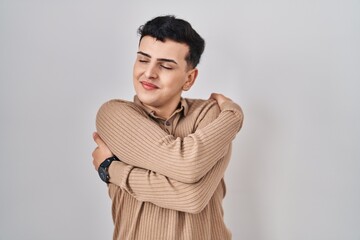 Poster - Non binary person standing over isolated background hugging oneself happy and positive, smiling confident. self love and self care