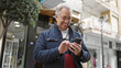 © Krakenimages.com - Middle age man with grey hair using smartphone smiling at street