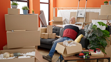 Poster - Middle age man with grey hair resting sitting on the sofa at new home