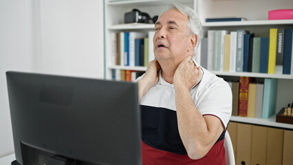 Canvas Print - Middle age man with grey hair teacher using computer with neck pain at university classroom