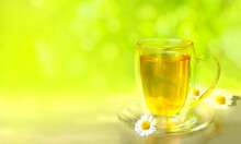 Herbal Tea With Chamomile Flowers In A Glass Cup On  Summer Background With Copy Space.  Phyto Tea From Chamomile In Summertime.