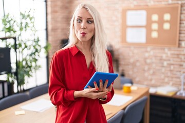 Sticker - Caucasian woman working at the office with tablet making fish face with lips, crazy and comical gesture. funny expression.