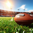 close up of American football pigskin on the grass field with blurred empty Stadium ranks in the background