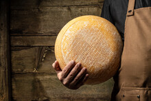 Big Yellow Cheese Wheel In Seller Hands. Cheese In Man's Cheesemaker Hands. Marble Cheese