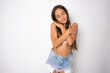 © Danko - Young beautiful child girl wearing summer clothing standing over isolated white background Hugging oneself happy and positive, smiling confident. Self love and self care