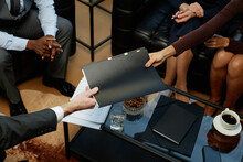 Top View Closeup Of Business People Handing Binder With Documents Over Coffee Table During Meeting In Luxury Office, Copy Space
