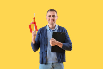 Canvas Print - Mature man with flag of Spain and clipboard on yellow background