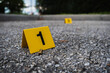 A group of yellow crime scene evidence markers on the street after a gun shooting brass bullet shell casing rifle