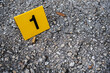 One yellow crime scene evidence marker on the street after a gun shooting brass bullet shell casing 9mm handgun pistol