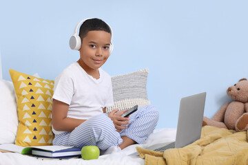 Poster - Little African-American boy with mobile phone studying computer sciences online in bedroom