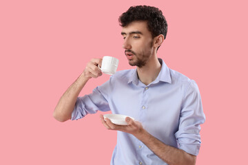 Wall Mural - Young businessman with cup of coffee on pink background