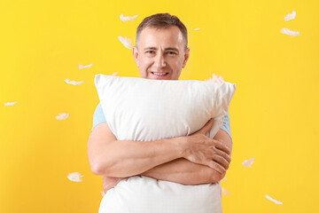 Poster - Mature man with soft pillow and feathers on yellow background