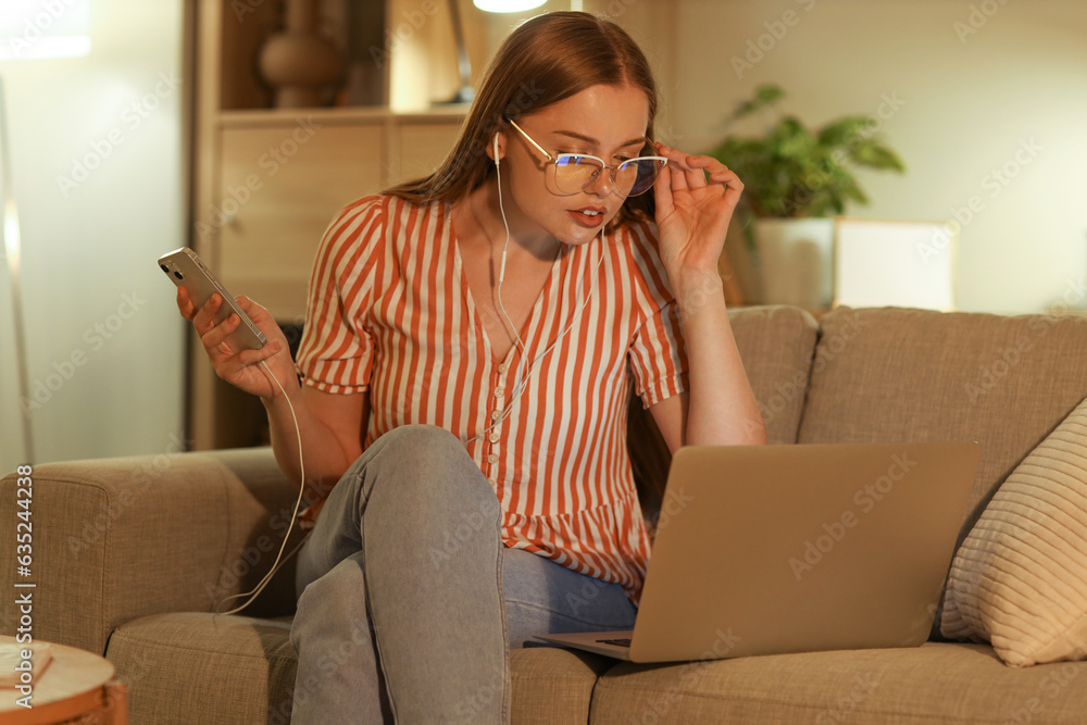 Young woman working with mobile phone at home in evening